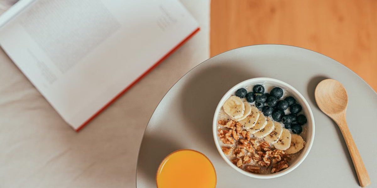 Top view of healthy breakfast with oatmeal, fresh fruit, and orange juice on a tray.