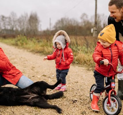 Happy family enjoying quality time outdoors with kids and dog in countryside.